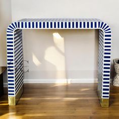 a blue and white console table sitting on top of a hard wood floor next to a vase