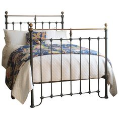 an iron bed frame with pillows and blankets on it