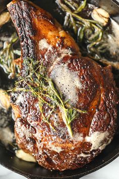 a roasting pan filled with meat covered in herbs and seasonings on top of a white table