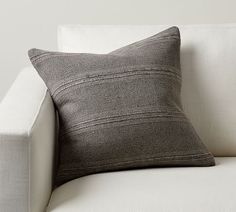 a black and white pillow sitting on top of a white couch next to a wall