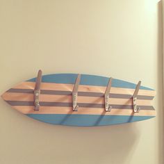 a surfboard mounted to the side of a wall with five hooks on each end