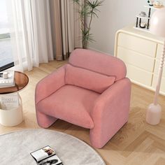 a pink chair sitting on top of a hard wood floor next to a white table