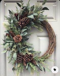 a wreath with pine cones and greenery is hanging on the front door to welcome guests