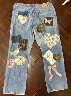 an old pair of jeans with patches and flowers on them sitting on a wooden floor