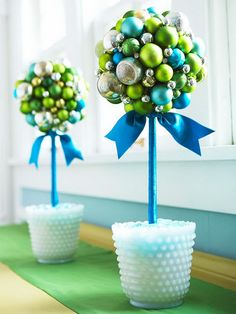 two vases with balls and bows on them sitting on a table in front of a window