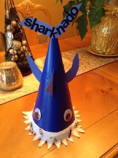 a blue shark hat sitting on top of a wooden table next to a potted plant