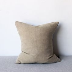 a beige pillow sitting on top of a bed next to a white wall and floor