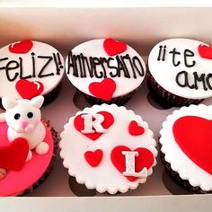 cupcakes in a box decorated with red and white frosting, including the letters i love you