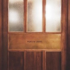 a wooden door with frosted glass and the words peas & leeks on it