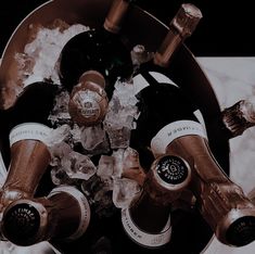 several bottles of wine in an ice bucket on a marble table with water and ice