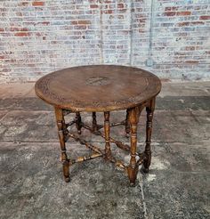 an old wooden table sitting in front of a brick wall