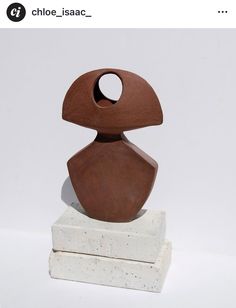 a brown sculpture sitting on top of a white block with a hole in it's center