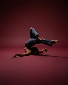 a man is doing a handstand on the floor in front of a red background