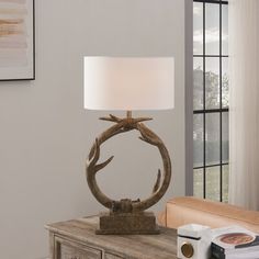 a table lamp that is on top of a wooden table with a white shade over it