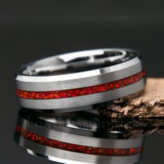 two wedding bands with red and silver inlays are shown next to each other