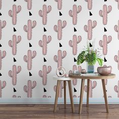 a cactus wallpaper with pink and black shapes on it, next to a small table