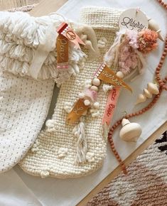 two pieces of white knitted clothing on top of a wooden floor next to beads and necklaces