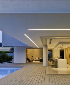 an open living room and dining area next to a swimming pool in a modern house