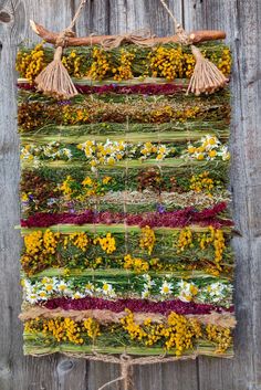 a wall hanging made out of flowers and grass on a wooden fence with twine