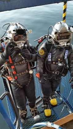 two men in diving suits standing on a boat