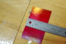 a wooden table with a ruler on it and a piece of red paper next to it