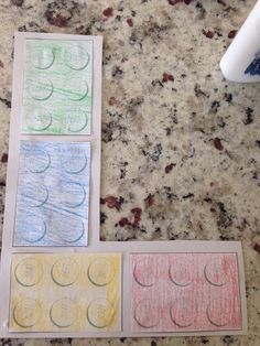 four different colored paper squares sitting on top of a marble counter next to a paint roller