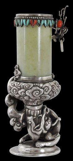 a silver candle holder with an elephant on it's legs and a red bead around the top