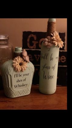 two glass bottles with flowers on them are sitting on a table next to each other