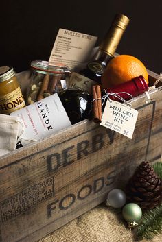 a wooden crate filled with lots of different types of food and wine bottles on top of a table