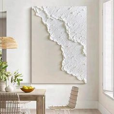 a dining room table with chairs and a painting on the wall above it that is covered in white paint