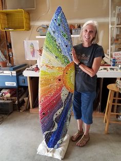 a woman is holding a colorful umbrella in her workshop with other work on the wall behind her