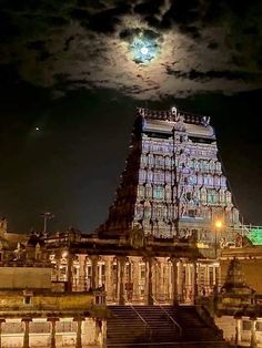 a full moon is seen over the top of an old building at night with steps leading up to it