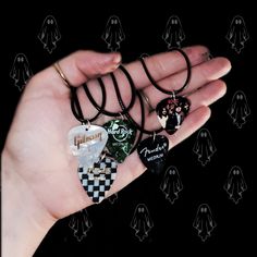 a person's hand holding four different necklaces in their palm, with black and white designs on them