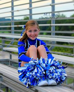 a cheerleader sitting on the bleachers with her pom - poms