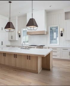 a large kitchen with two pendant lights hanging from the ceiling