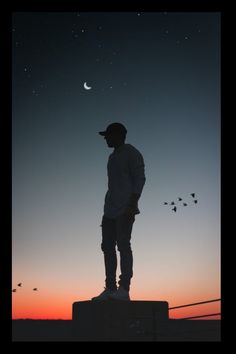 a man standing on top of a cement block under a sky filled with stars and the moon