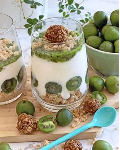 two glasses filled with yogurt and kiwis on a wooden cutting board