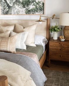 a bedroom with a bed, nightstand and painting on the wall above it's headboard