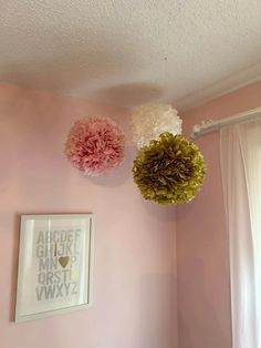 three pom - poms hanging from the ceiling in a pink room with white curtains