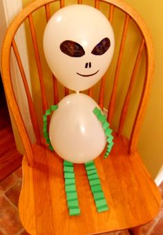 an alien balloon sitting on top of a wooden chair