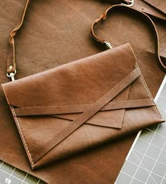 a brown leather purse sitting on top of a piece of paper next to a pair of scissors