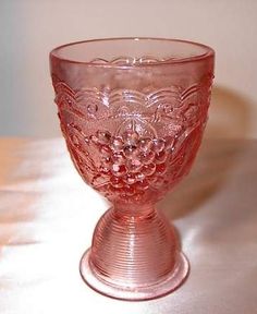 a pink glass cup sitting on top of a table