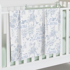 a white crib with two blue and white towels hanging from it's rails