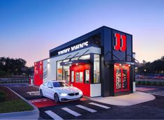 a white car is parked in front of a small restaurant with red and black trim