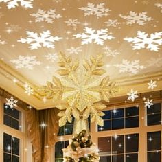 a christmas tree in the middle of a living room with snowflakes on the ceiling