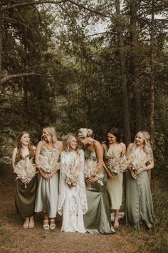 a group of women standing next to each other in front of some trees and grass