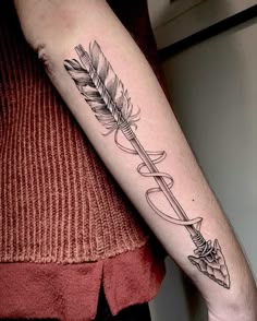 a woman's arm with a feather and arrow tattoo on the left inner forearm