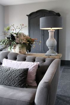 a living room with a couch, lamp and flowers on the table