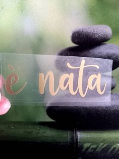 a person holding up a sign with the word natta on it in front of some rocks