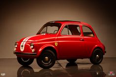 an old red car sitting on top of a black floor